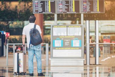 Havaalanı uçuş bilgileri panosunda bakarak turist adam