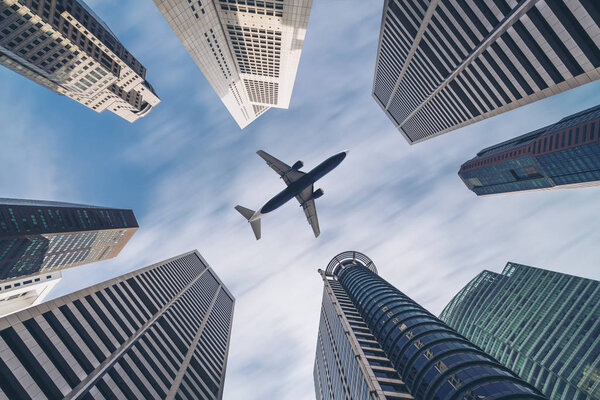 Airplane flying over city buildings, high-rise business skyscrapers. Tourism, transport, transportation, travel by airplane. Airplane transportation in center. City surround airplane transportation.