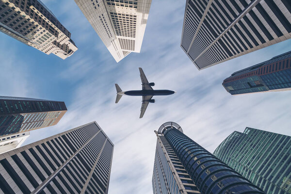 Airplane flying over city buildings, high-rise business skyscrapers. Tourism, transport, transportation, travel by airplane. Airplane transportation in center. City surround airplane transportation.