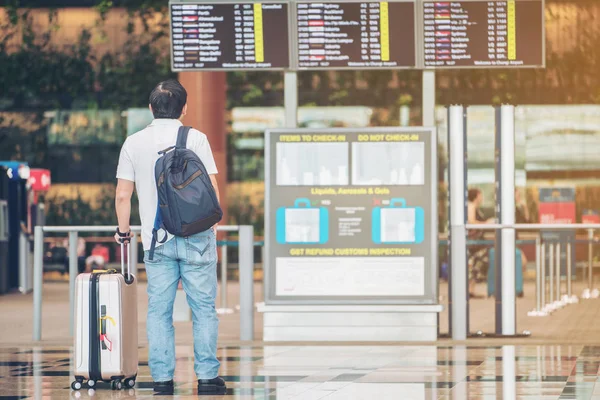 Toeristische man kijken vlucht informatiebord in luchthaven — Stockfoto