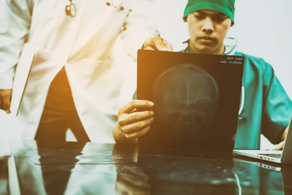 Врачи смотрят рентгеновские снимки головы пациента — стоковое фото