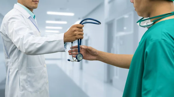Doctor giving stethoscope to surgeon (Referral)