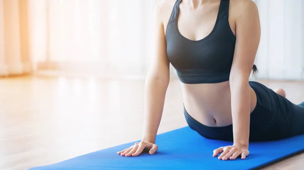 Ung kvinna utövar i inomhus gym på yogamatta — Stockfoto