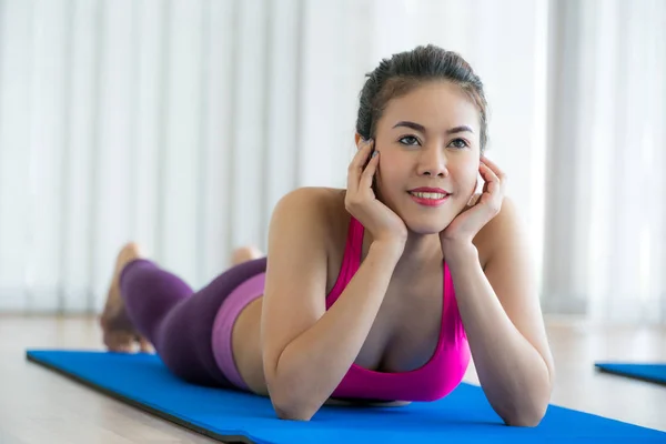 Mujer feliz joven relajándose en la esterilla de yoga en el gimnasio —  Fotos de Stock
