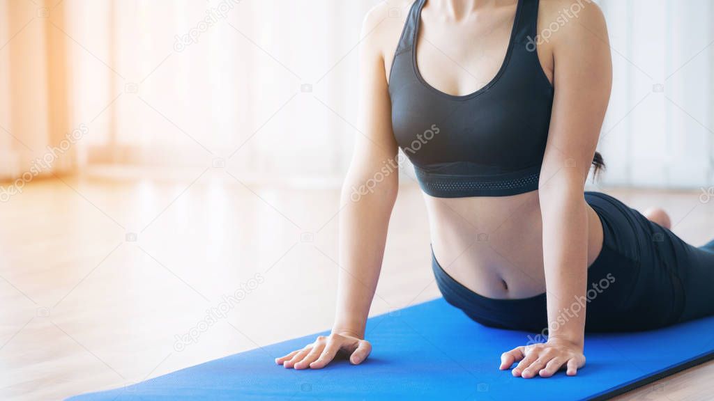 Young woman exercising in indoor gym on yoga mat