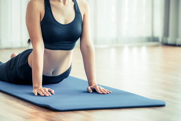 Mujer joven haciendo ejercicio en el gimnasio interior en la esterilla de yoga —  Fotos de Stock
