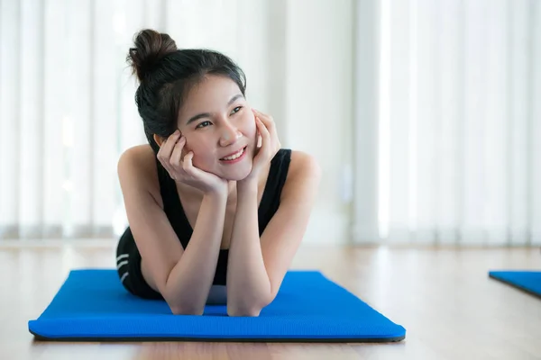 年轻快乐的女人躺在上，在健身房瑜伽垫上 — 图库照片