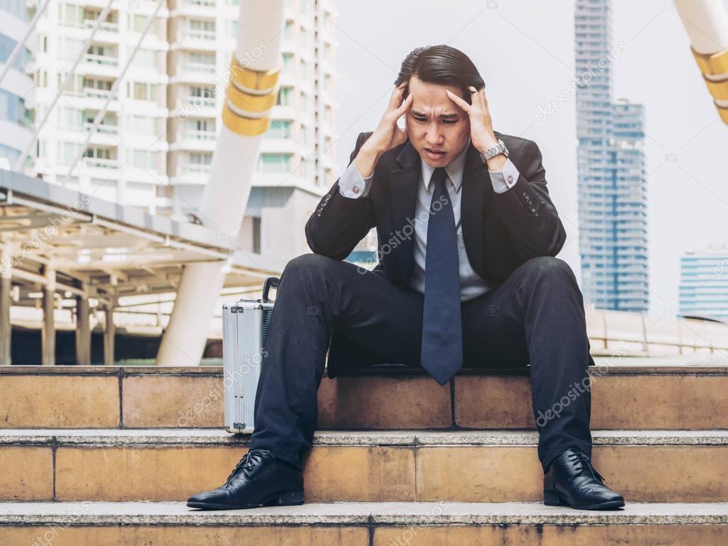 Desperate businessman sitting hopelessly on stair floor