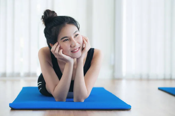 Gelukkig jongedame ontspannen op yoga mat in sportschool — Stockfoto