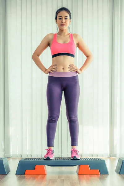 Deportiva mujer de pie en aeróbico stepper en gimnasio — Foto de Stock
