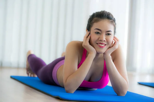 年轻快乐的女人躺在上，在健身房瑜伽垫上 — 图库照片