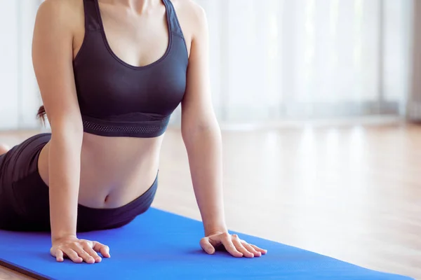 Mujer joven haciendo ejercicio en el gimnasio interior en la esterilla de yoga —  Fotos de Stock