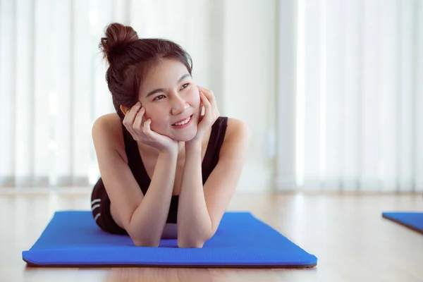 Jeune femme heureuse se détendre sur tapis de yoga dans la salle de gym — Photo