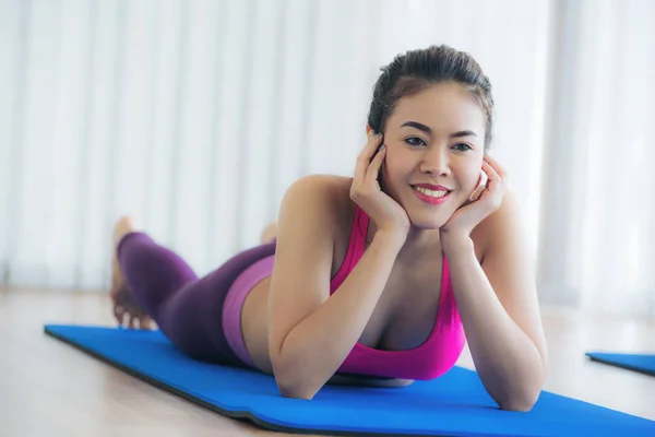 Młoda kobieta szczęśliwa relaksujący na matę do jogi w siłowni — Zdjęcie stockowe
