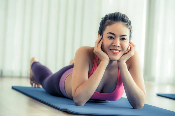 Mujer feliz joven relajándose en la esterilla de yoga en el gimnasio —  Fotos de Stock