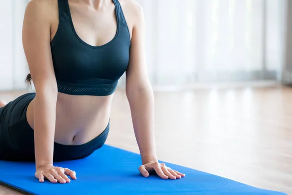 Mujer joven haciendo ejercicio en el gimnasio interior en la esterilla de yoga — Foto de Stock