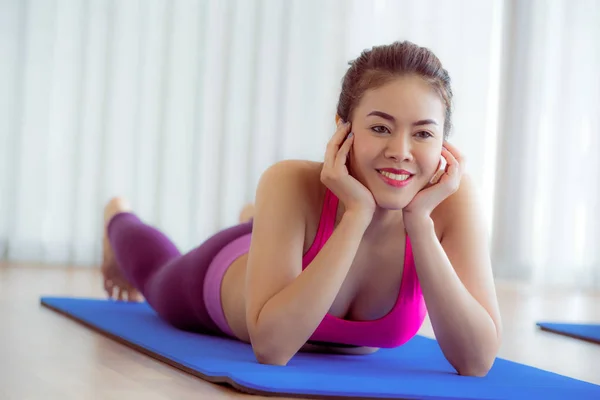 Mujer feliz joven relajándose en la esterilla de yoga en el gimnasio —  Fotos de Stock