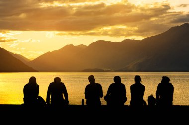 Sahilde oturan genç insanlar siluet grup