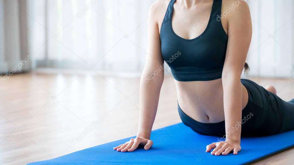 Young woman exercising in indoor gym on yoga mat