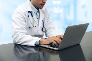 Dizüstü bilgisayar ile masa üzerinde çalışan doktor