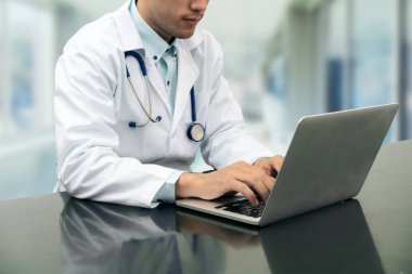 Dizüstü bilgisayar ile masa üzerinde çalışan doktor