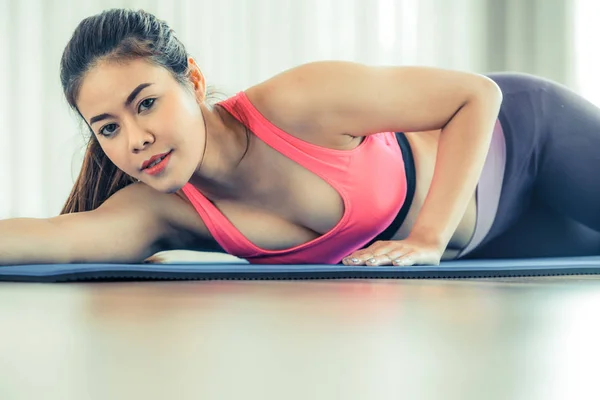 Mujer feliz joven relajándose en la esterilla de yoga en el gimnasio — Foto de Stock