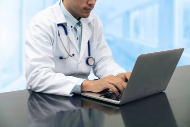 Dizüstü bilgisayar ile masa üzerinde çalışan doktor