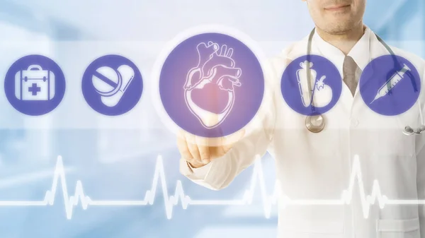 Doctor pointing at heart icon on blue background. — Stock Photo, Image