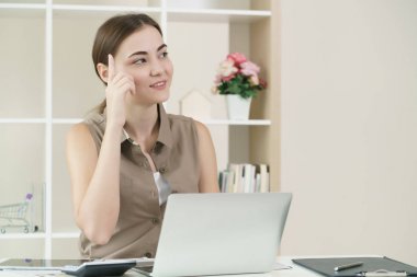 Kadın düşünüyor ve ofiste bilgisayar çalışır.