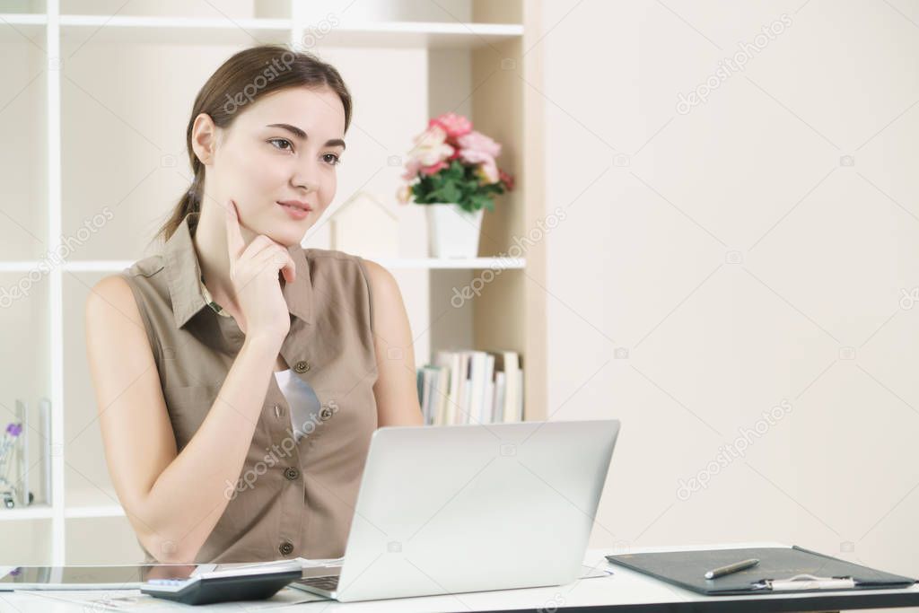 Woman thinks and works on computer in office.
