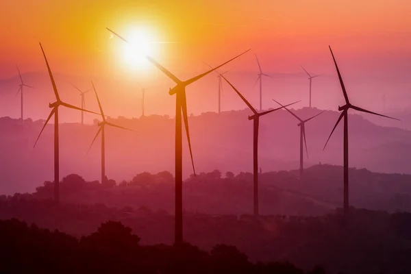 Turbine eoliche silhouette sulle montagne al tramonto . — Foto Stock