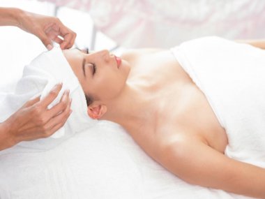 Rahatlamış genç bir kadın masaj için spa yatağında yatıyor..