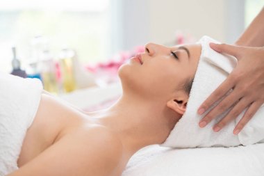 Rahatlamış genç bir kadın masaj için spa yatağında yatıyor..