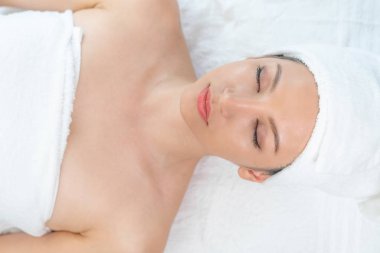 Rahatlamış genç bir kadın masaj için spa yatağında yatıyor..