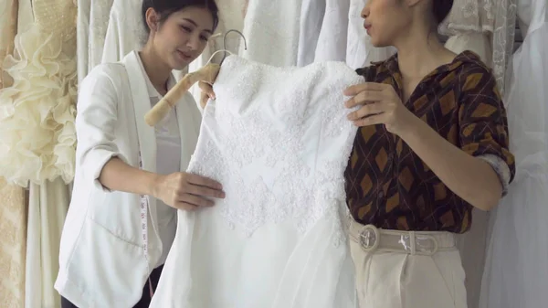 Future bride customer talking with wedding store shopkeeper to buy wedding dress and accessories for her upcoming wedding ceremony.