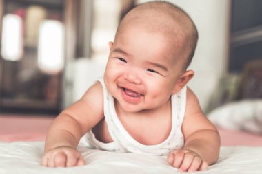 İlk kez gülümseyen şirin bir bebek emekliyor. Mutlu Asyalı bebek yatak odasında oynuyor..