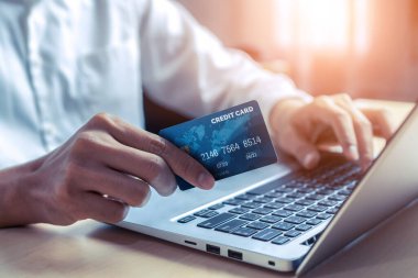 Genç adam, laptop bilgisayar başvurusu ya da web sitesinde online alışveriş yapmak için kredi kartı kullanıyor. E-ticaret ve online alışveriş kavramı.