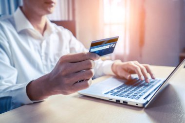 Genç adam, laptop bilgisayar başvurusu ya da web sitesinde online alışveriş yapmak için kredi kartı kullanıyor. E-ticaret ve online alışveriş kavramı.