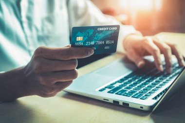 Genç adam, laptop bilgisayar başvurusu ya da web sitesinde online alışveriş yapmak için kredi kartı kullanıyor. E-ticaret ve online alışveriş kavramı.