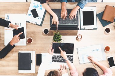 Modern ofisteki iş adamları ve iş kadınlarıyla grup toplantısındaki iş adamlarının en üst düzey görüşü, masada dizüstü bilgisayar, kahve ve belge ile. Şirket ortaklığı konsepti..