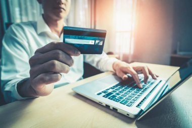 Genç adam, laptop bilgisayar başvurusu ya da web sitesinde online alışveriş yapmak için kredi kartı kullanıyor. E-ticaret ve online alışveriş kavramı.