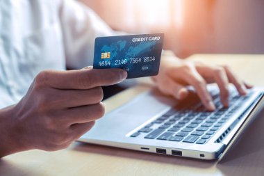 Genç adam, laptop bilgisayar başvurusu ya da web sitesinde online alışveriş yapmak için kredi kartı kullanıyor. E-ticaret ve online alışveriş kavramı.