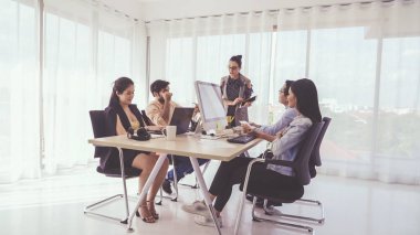 Kıdemli lider takım üyelerine tavsiye konuşması yapıyor. Modern ofisteki masada yaratıcı iş adamları buluşuyor. Çok kültürlü iş ekibi..