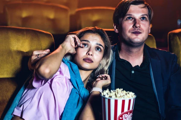 Caucasian man and woman watching a sad movie and his girlfriend crying