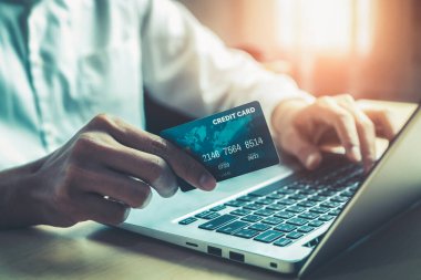 Genç adam, laptop bilgisayar başvurusu ya da web sitesinde online alışveriş yapmak için kredi kartı kullanıyor. E-ticaret ve online alışveriş kavramı.