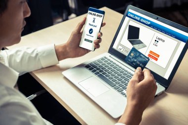 Genç adam, laptop bilgisayar başvurusu ya da web sitesinde online alışveriş yapmak için kredi kartı kullanıyor. E-ticaret ve online alışveriş kavramı.