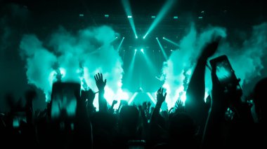 Mutlu insanlar gece kulübü DJ parti konserinde dans eder ve sahnede DJ 'den elektronik dans müziği dinlerler. Siluet dolu neşeli kalabalık 2020 yılbaşı partisini kutluyor. İnsanların yaşam tarzı DJ gece hayatı.