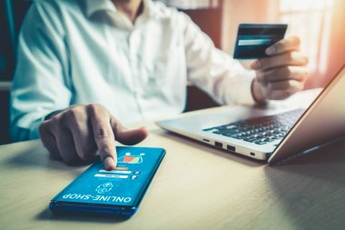Genç adam, laptop bilgisayar başvurusu ya da web sitesinde online alışveriş yapmak için kredi kartı kullanıyor. E-ticaret ve online alışveriş kavramı.