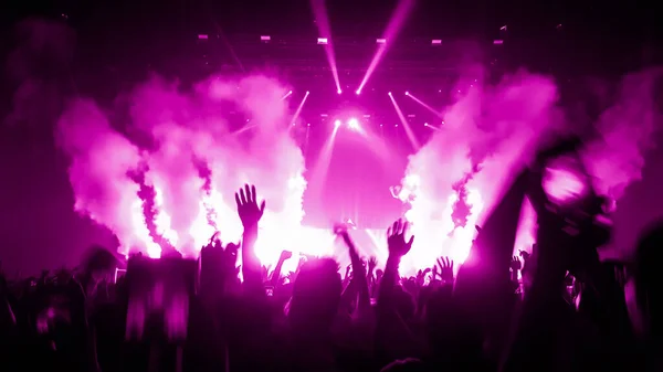 Happy people dance in nightclub DJ party concert and listen to electronic dancing music from DJ on the stage. Silhouette cheerful crowd celebrate New Year party 2020. People lifestyle DJ nightlife.