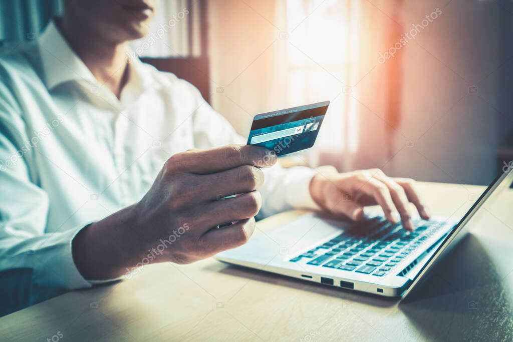 Young man use credit card for shopping payment online on laptop computer application or website. E-commerce and online shopping concept.